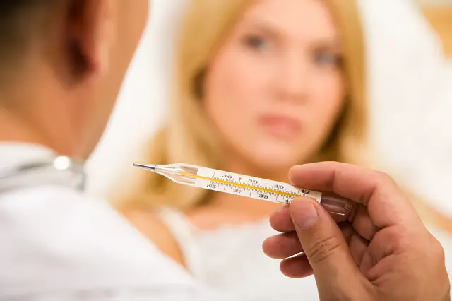 doctor's hand holding thermometer